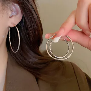 Minimalist silver circular hoop earrings featuring high-polish finish on a female model