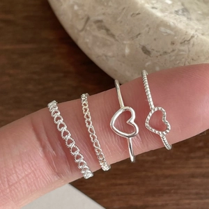 Close-up of four assorted 925 sterling silver heart rings for stylish layered wearing