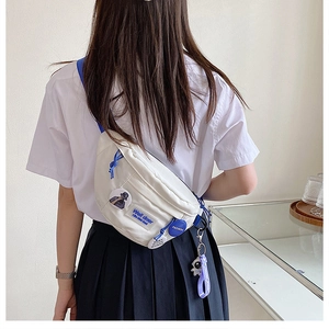 Detailed back view of a white canvas crossbody bag featuring blue zippers and badges
