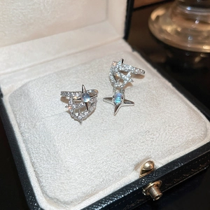 Close-up of asymmetric star-shaped silver ear cuffs with blue opal and tiny crystals