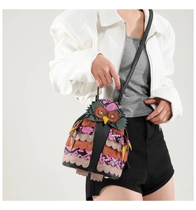 Detail of owl-shaped handbag with colorful patchwork, faux snake texture and 3D feathers