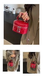 Detail of red quilted mini box bag with gold chain strap and heart charm accents
