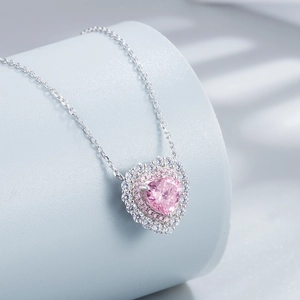Macro view of pink heart-shaped crystal pendant with double diamond halo in silver