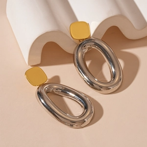 Macro detail of oval geometric earrings featuring gold and silver dual-tone metallic finish