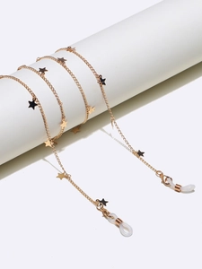 Detail of gold eyewear chain with star charms on white cylinder display stand