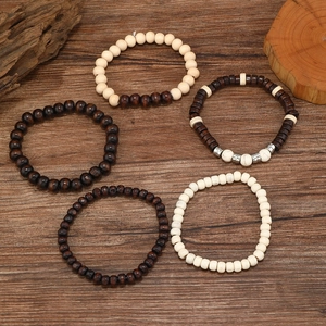 Macro detail of multi-layer wood and coconut shell beaded bracelets on a wooden surface