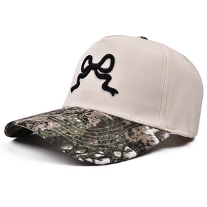 Dettaglio cappellino beige con ricamo a fiocco nero e visiera a stampa mimetica