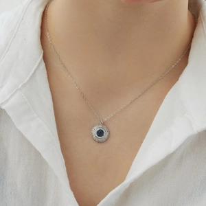 Detail of S925 sterling silver evil eye necklace with zircon on a person wearing a white shirt