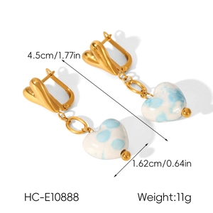 Détail de boucles d'oreilles cœur dorées avec pendentifs en céramique tachetés de bleu