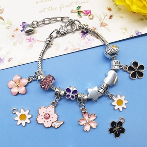 Detail of DIY charm bracelet with multi-colored enamel flowers and silver Peace bead