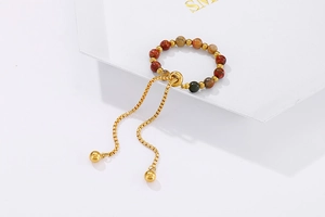 Detail of adjustable gold bead bracelet featuring natural reddish-brown stone beads