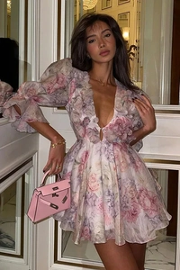 Détail de robe en mousseline fleurie avec décolleté en V, manches bouffantes et sac rose