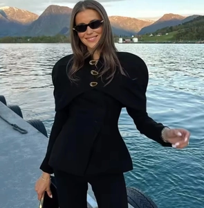 Detail of black stand-collar blazer with exaggerated puff sleeves and gold buttons