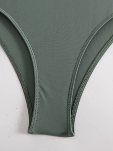 Détail de la couture double renforcée et du tissu élastique vert olive du maillot de surf