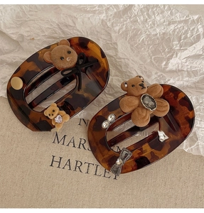 Retro hair clips with tortoiseshell texture, flocked bears, and rhinestones on beige canvas