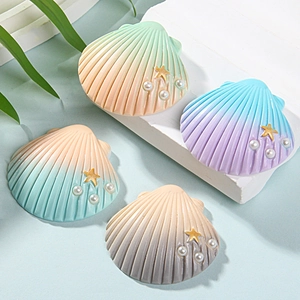 Close-up of colorful resin shell charms with gold stars and pearls for DIY crafts