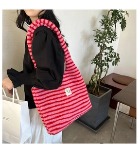 Close-up of pink striped plush tote bag featuring a white square brand label