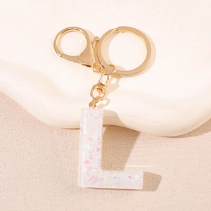 Détail du porte-clés lettre L en résine avec paillettes et fermoir doré chic