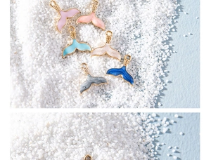 Macro shot of colorful fish tail pendants with gold edges on white sand background