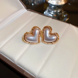 Elegant gold heart earrings with pearl inlay on white ribbed jewelry display box