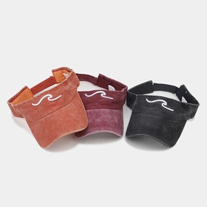 Dettaglio di tre visiere in cotone lavato con ricamo a onde nei colori arancio, rosso e grigio