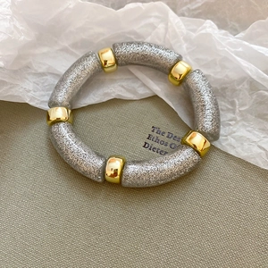 Close-up of iridescent acrylic bead bracelet with silver glitter and gold metal spacers