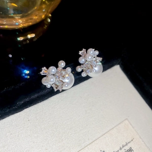 Detail of elegant pearl cluster earrings with sparkling cubic zirconia on a dark surface