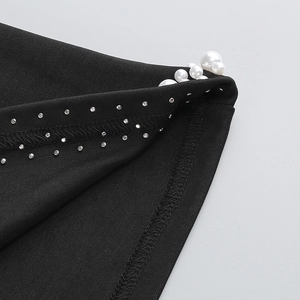 Detail of black fabric with elegant white pearls and silver rhinestone trim decoration