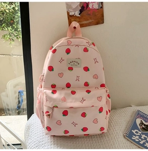 Detail shot of pink strawberry print backpack with Fashion Mummy Bag label on texture fabric