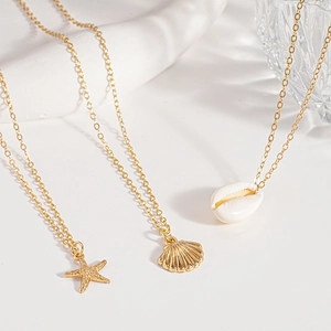 Detailed shot of gold starfish shell and conch pendants on 3-piece necklace set