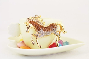 Detailed close-up of a golden horse keychain featuring orange and clear rhinestones
