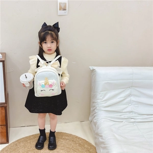 Cute kids unicorn backpack with glitter and stars worn by a young girl in a cozy room