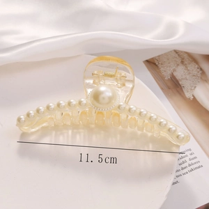 Detailed close-up of 11.5cm hollow pearl hair claw clip on soft white silk fabric