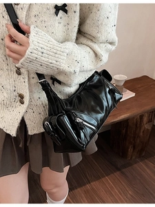 Retro black glossy patent leather crossbody bag with silver zipper in a lifestyle setting