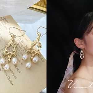 Detail of vintage baroque hollow gold earrings with three teardrop white pearls