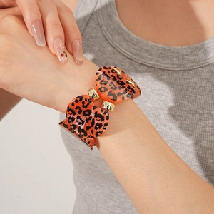 Detail of leopard print heart charms on a gold bracelet worn on a female wrist