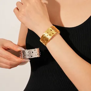 Wide textured open bangle with hammered finish and hollow round perforations in gold and silver
