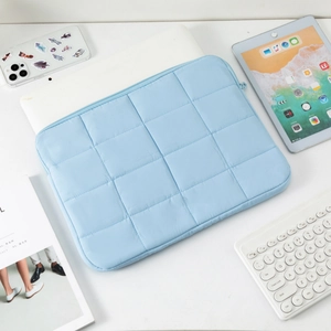 Detail of light blue quilted laptop sleeve with a smooth zipper and square pattern texture