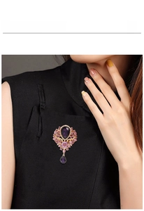 Detail of vintage purple crystal brooch with teardrop pendant worn on black fabric