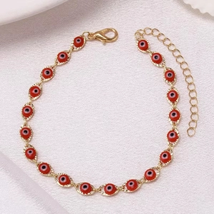 Close-up of golden anklet featuring red evil eye charms and adjustable chain extender