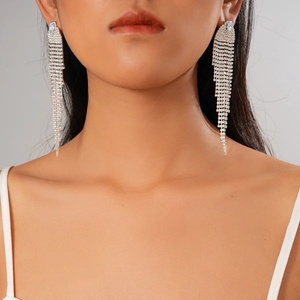 Close-up of elegant silver tassel earrings with zircons worn by a model on grey background