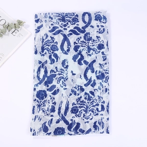 Detailed view of folded cotton linen scarf with blue floral prints and tassel texture