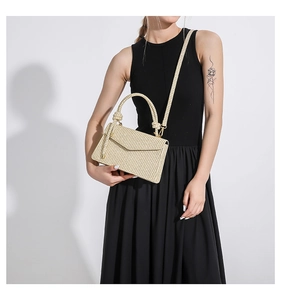 Detail of beige woven texture, elegant top handle and golden hardware on small square bag