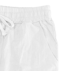 Detail of white linen trousers featuring elastic waistband and woven drawstring cords