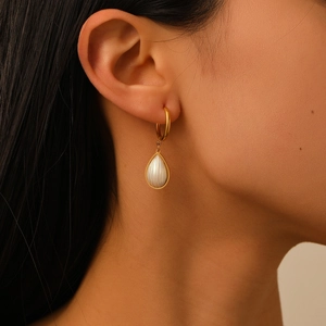 Close-up of a gold waterdrop earring with white shell texture on a female model