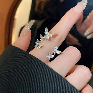 Detail view of a silver-tone multi-butterfly ring with pearls on a finger