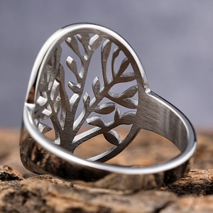 Gros plan détaillé d'une bague Arbre de Vie en argent sur un support en écorce