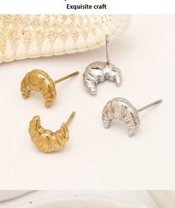 Close-up of gold and silver croissant studs showing textured stainless steel metal craft