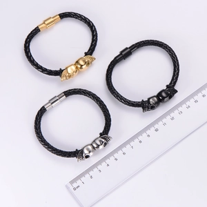 Close-up of punk leather bracelets with skull charms and magnetic clasps next to a ruler