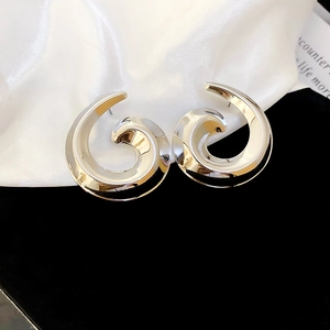 Macro detail of silver spiral wave stud earrings with a high-polished mirror finish